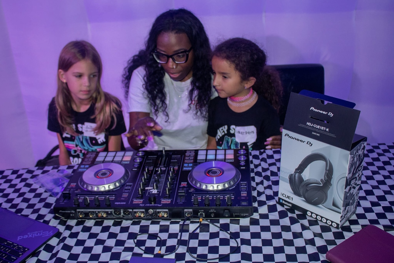 A First Spin instructor coaching two young students on a Pioneer DJ controller.