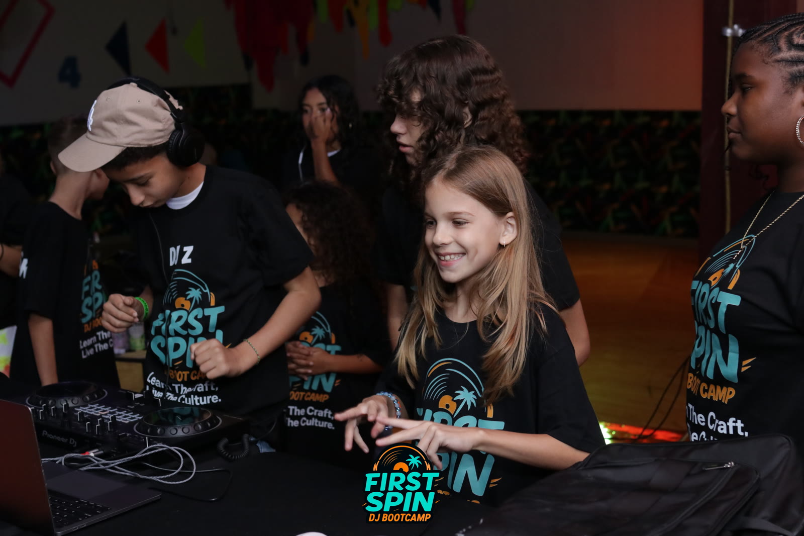 A First Spin student smiling at the DJ controller during camp.